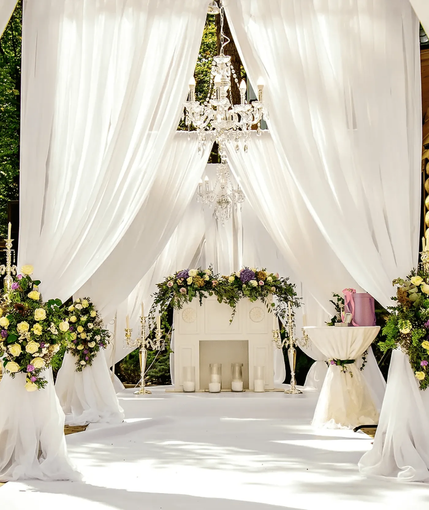 Tente blanche aménagé pour la reception d'un mariage avec des fleurs et des bougies